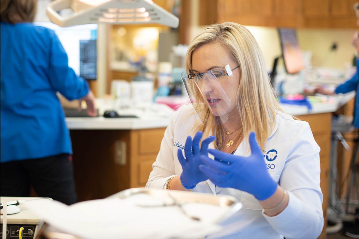 Orthodontic provider wearing protective eyewear and gloves preparing for patient care in a modern dental office