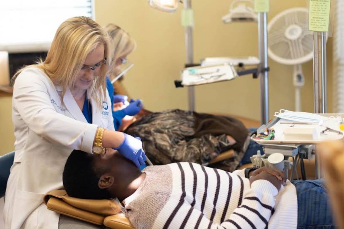 Orthodontic provider wearing gloves and protective eyewear providing chairside care to a patient during a treatment appointment