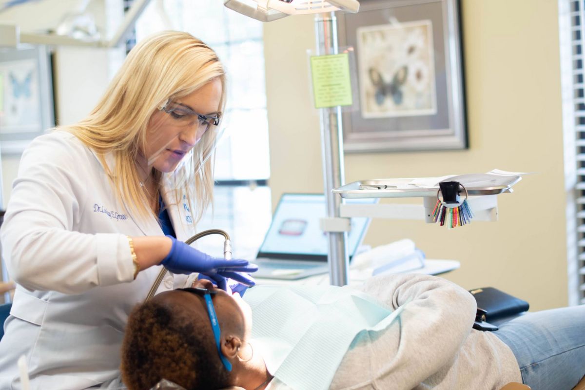 Orthodontic provider wearing protective eyewear and gloves performing dental treatment on a patient in a modern orthodontic office