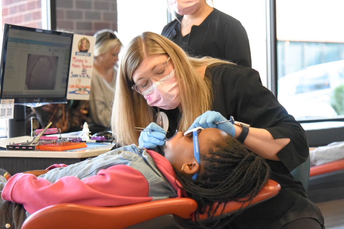 Orthodontic professional performing detailed dental work for a child patient during an appointment